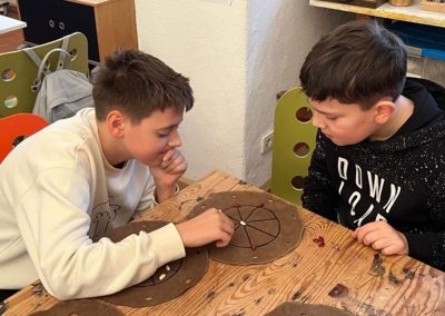 Zwei Schüler spielen mit der römischen Rundmühle.